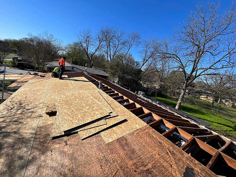 Close up of Juarez Contracting & Innovation LLC workers laying down wood panels on the wooden frame of a roof in the process of being installed